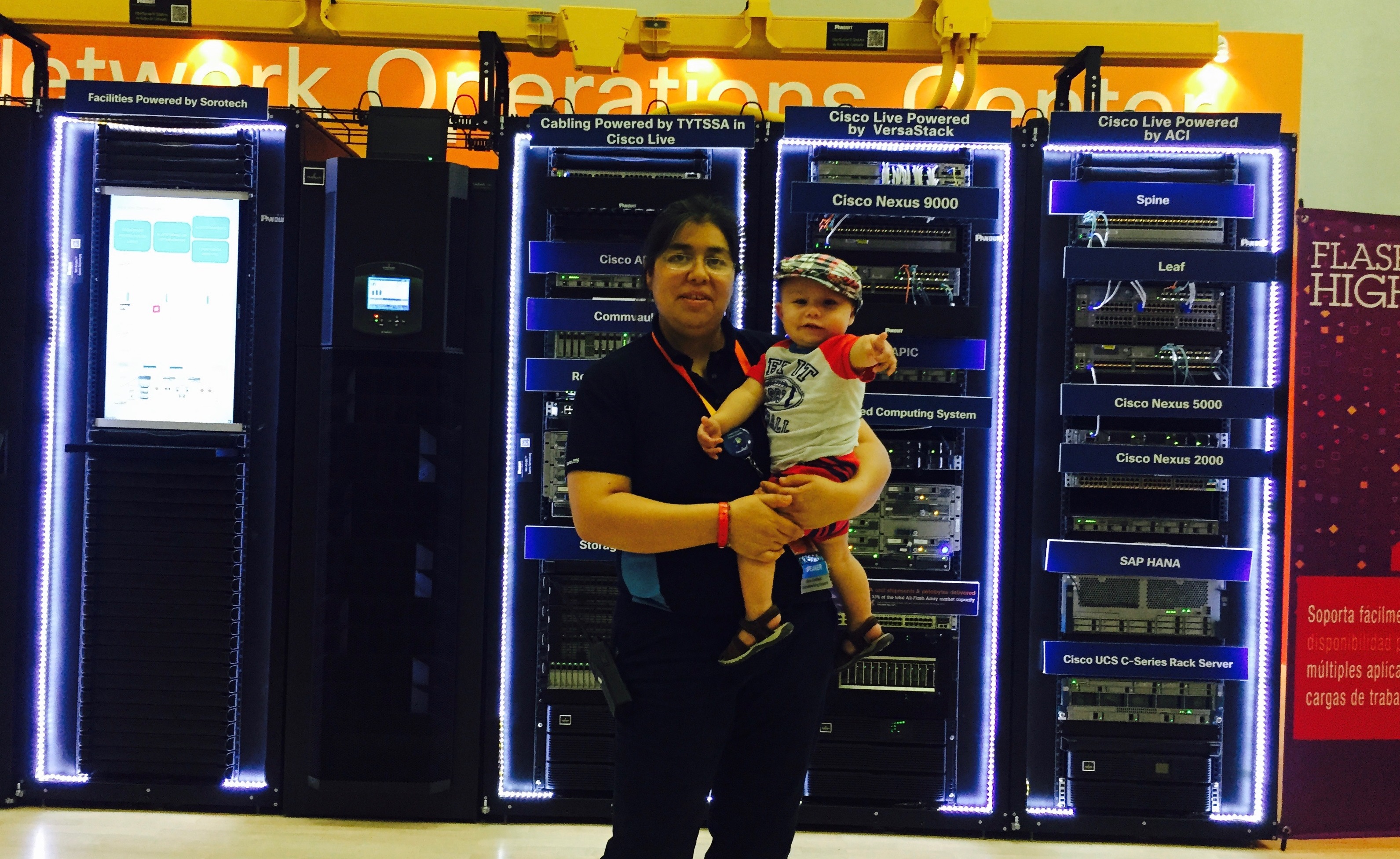 Roxana traveling for work with her baby and posing in front of computer gear.