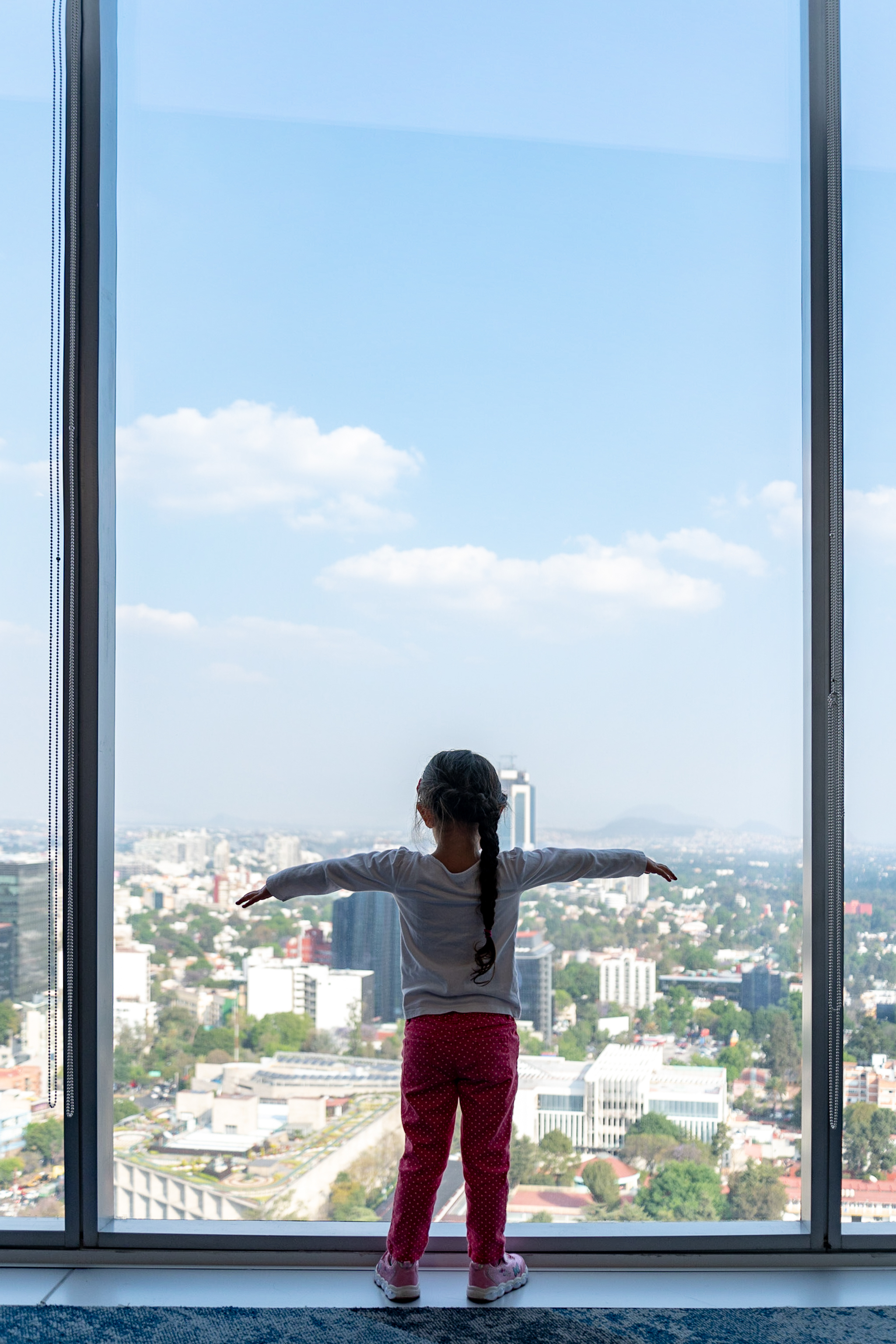Javier's daughter looking out windown overlooking Mexico City.