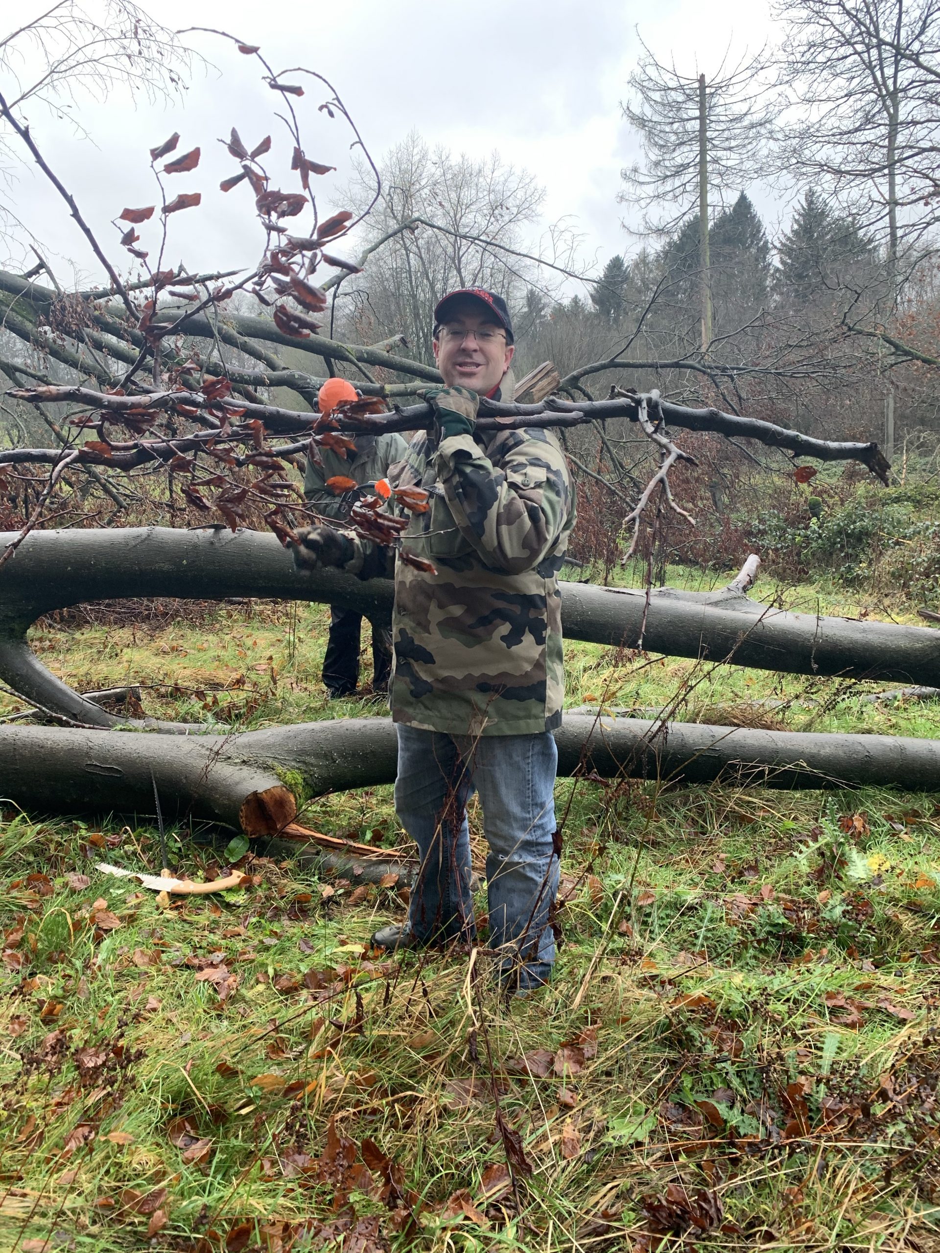 Hugues moves branches outside at a team give back event.