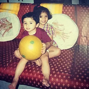Radhika and her cousin as children playing on a couch