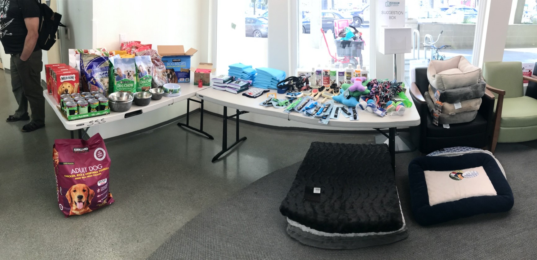 Two tables filled with pet supplies overflowing to the floor and nearby chairs at Second Street Studios in San Jose, California.