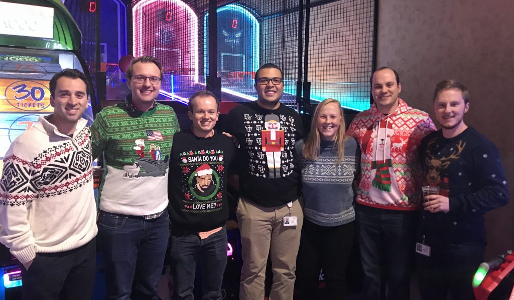 Julian's Cisco team wears holiday sweaters while posing for a group photo.