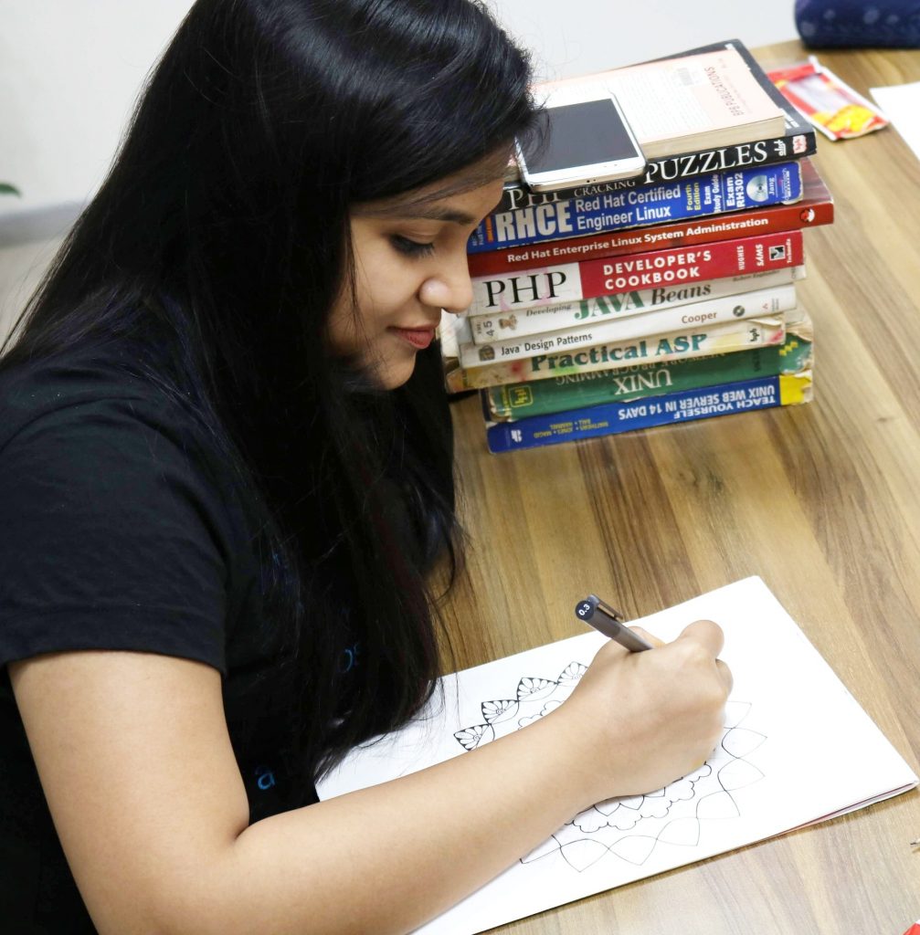 Diparati creating Mandala and Zentangle art next to a stack of books.