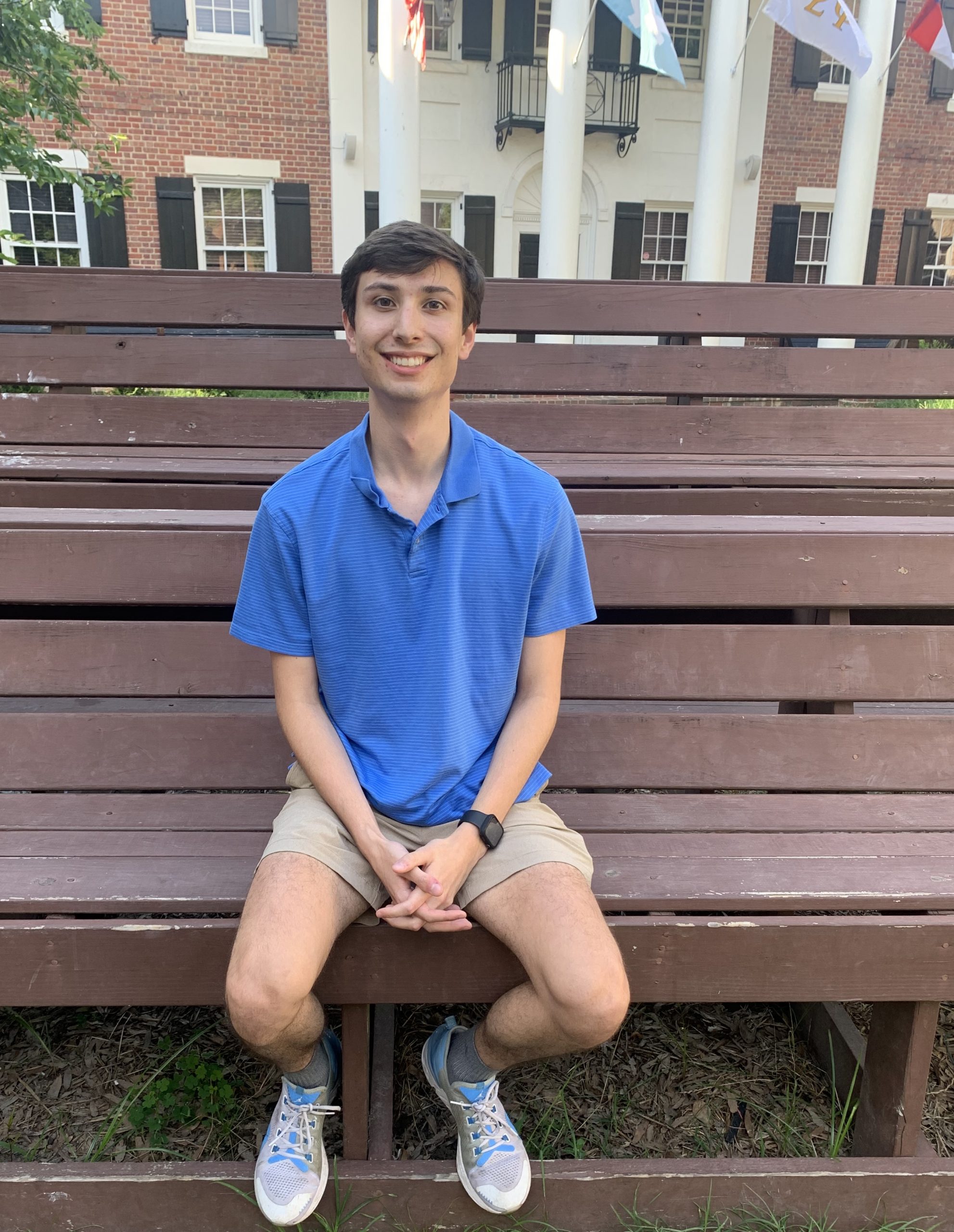 Drew smiles on a bench outside of a fraternity house at UNC Chapel Hill.
