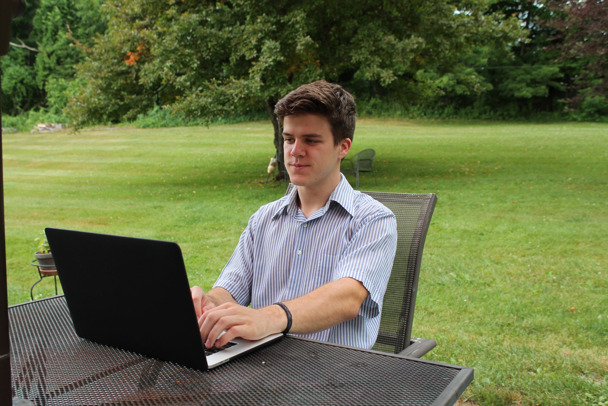 Carl sits outside while working on his laptop.