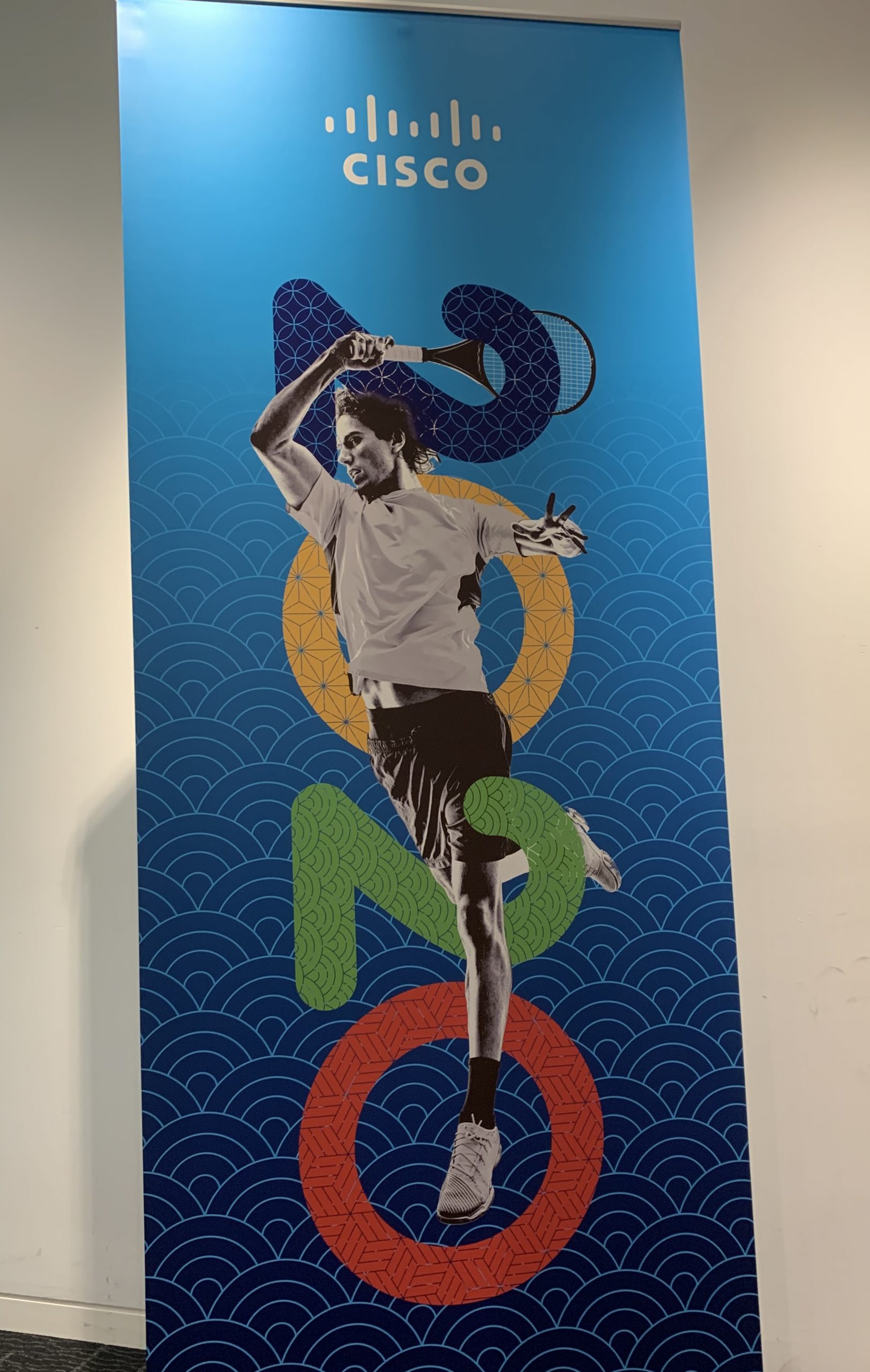 A Cisco banner with a person swinging a tennis racket intertwined with 2020