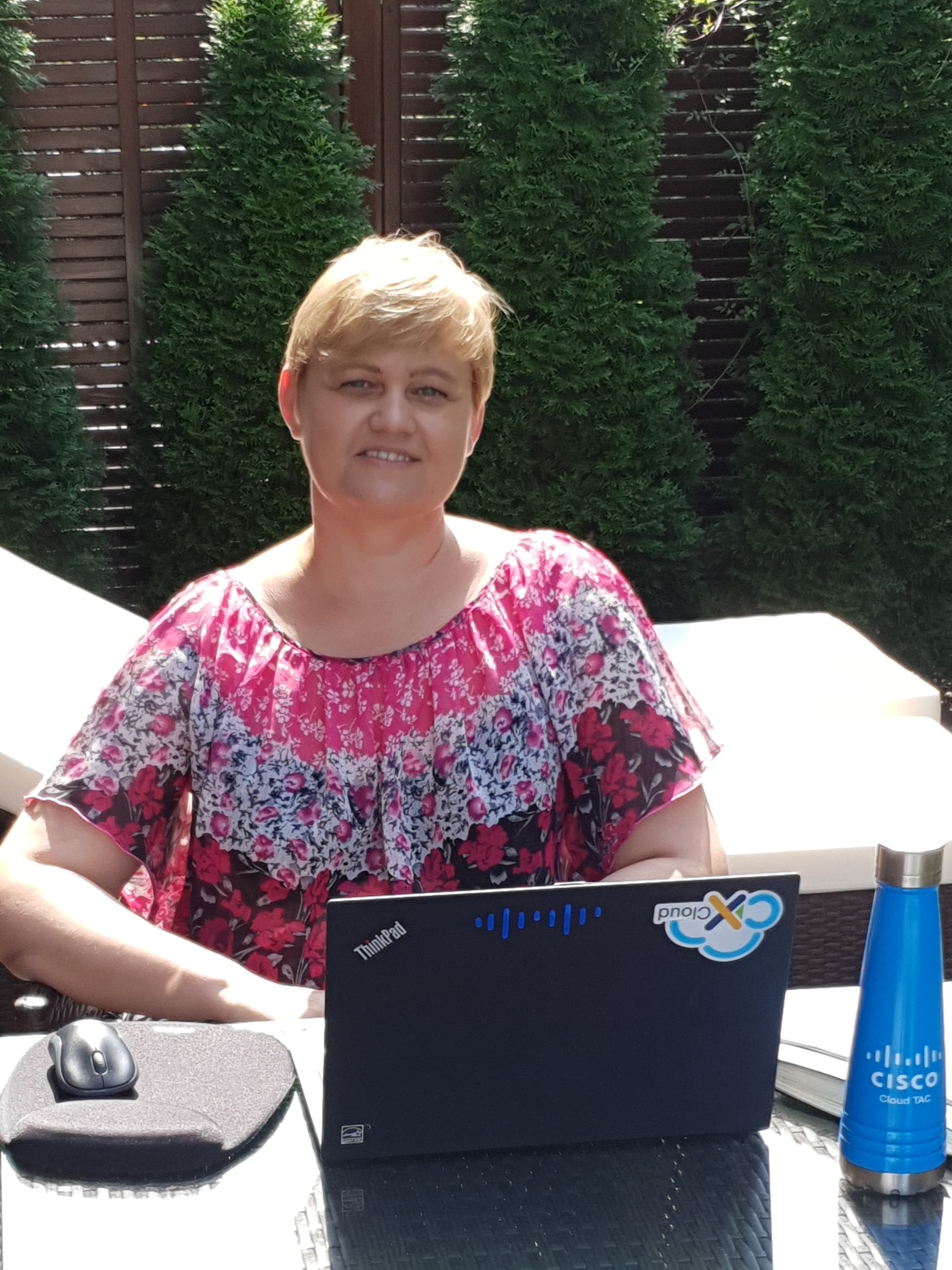 Danuta sits at computer in backyard.