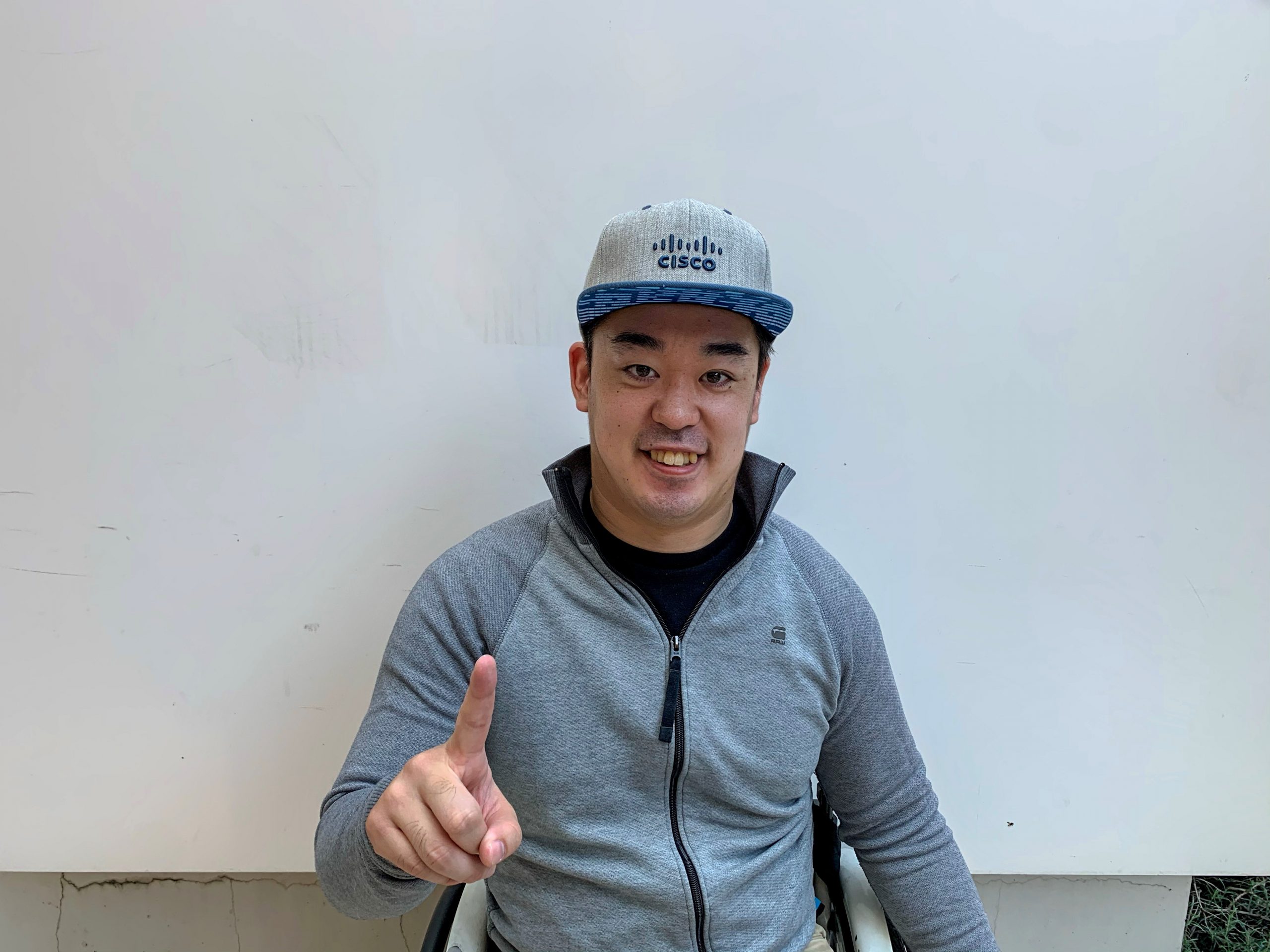 Hideaki wears a Cisco hat and holds up his finger as #1.