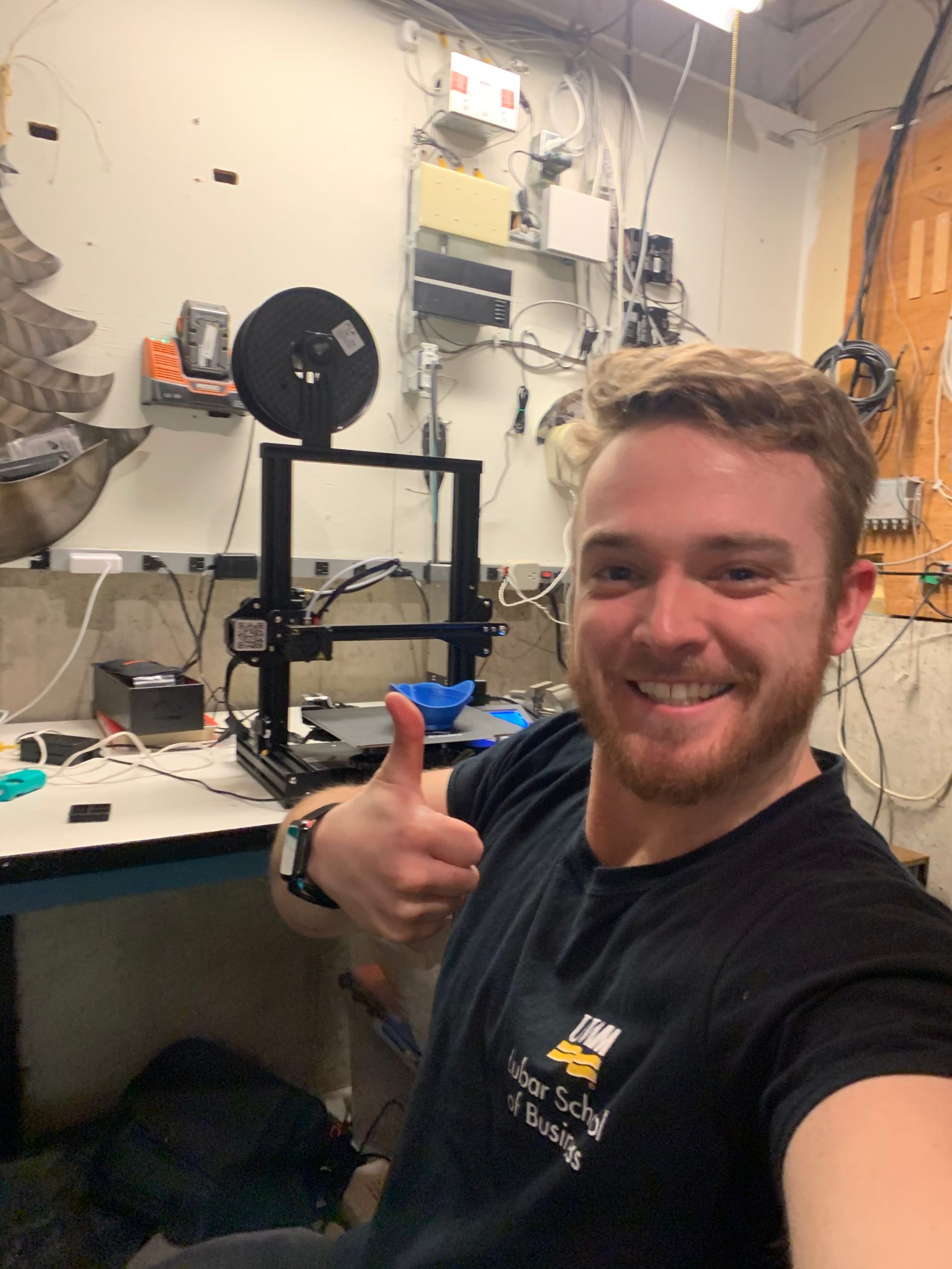 Nathan giving thumbs up in front of 3D printer. 