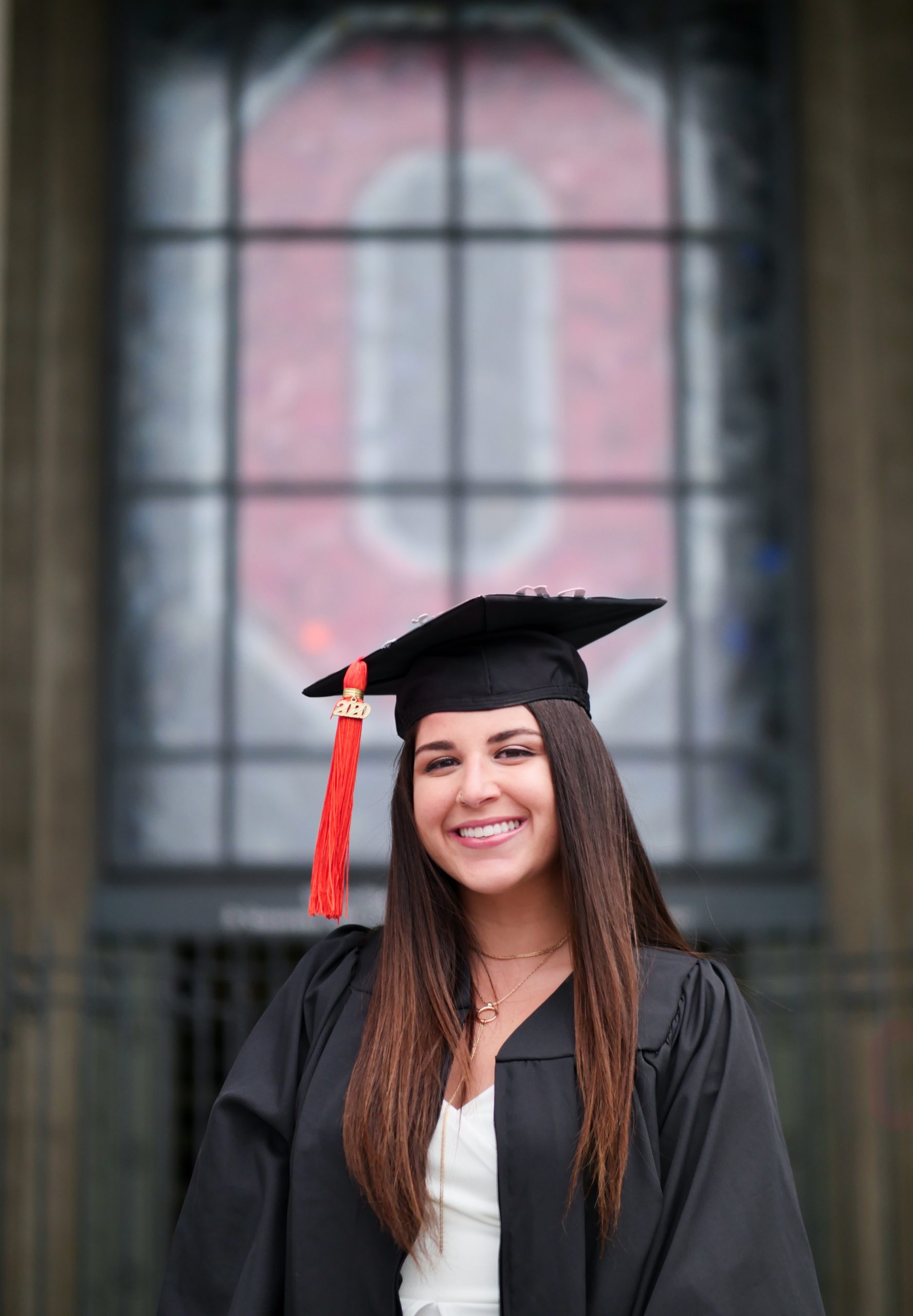 Rachel in cap and gown in front of Ohio State building. 