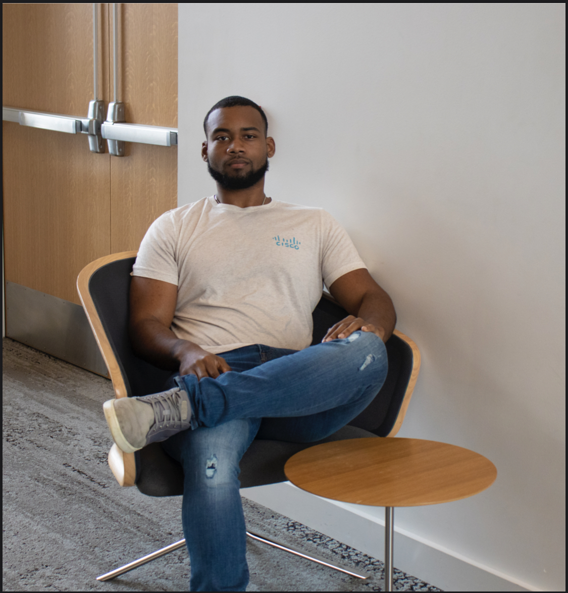Michael sitting in chair wearing Cisco shirt. 