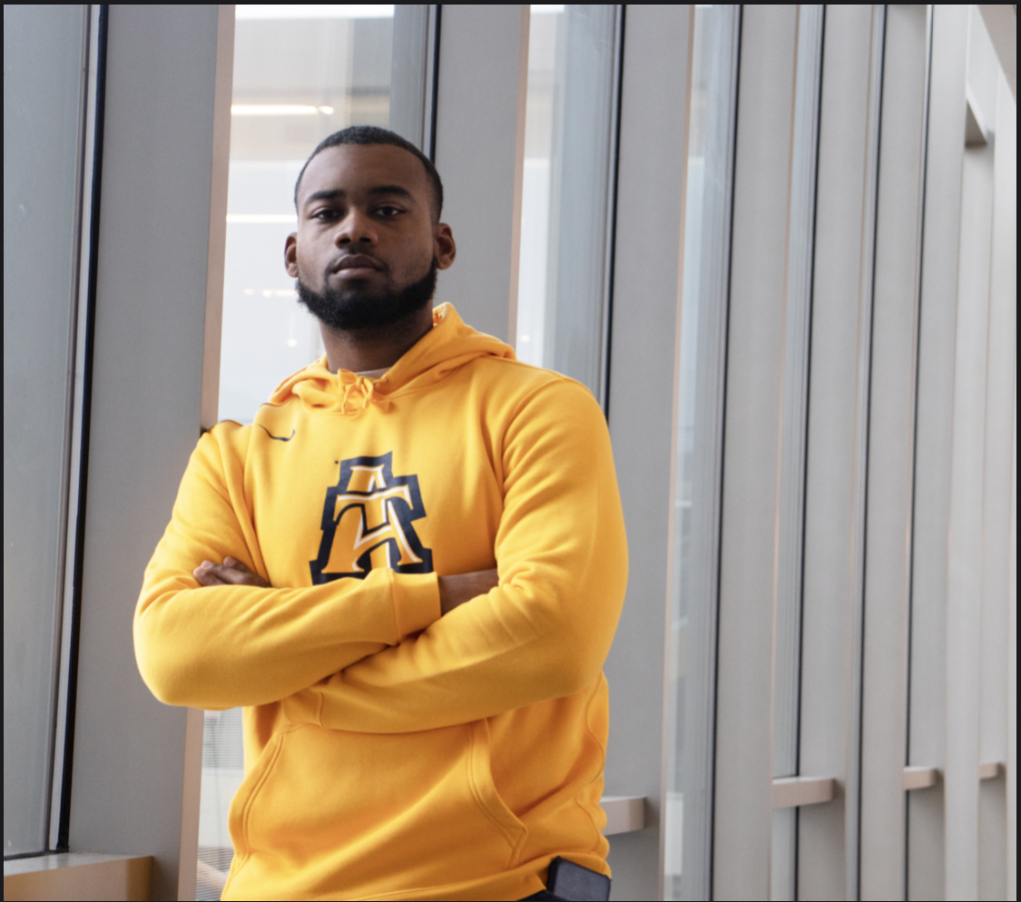 Michael leaning against wall looking at Camera.