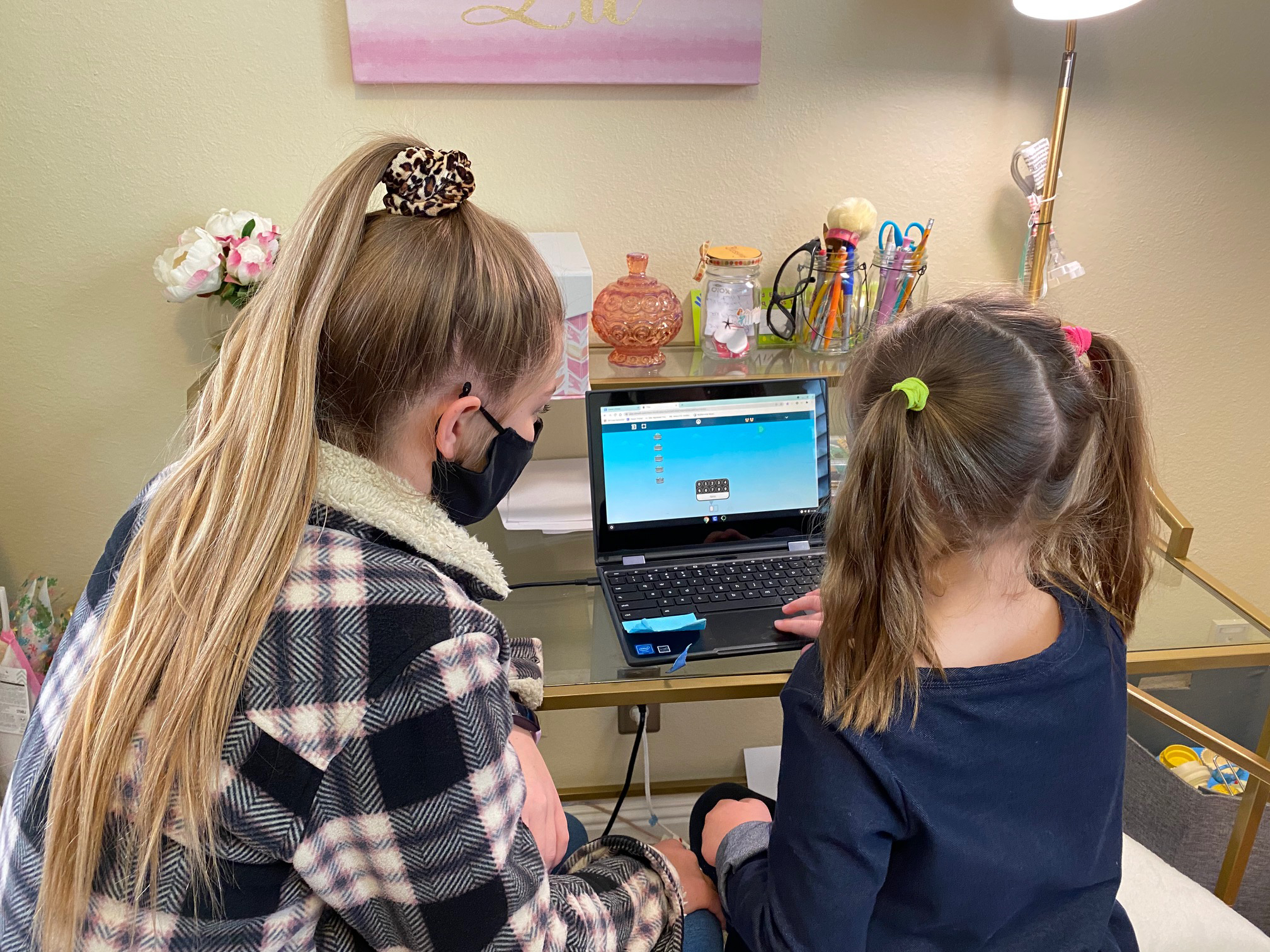 A child and adult work at computer.