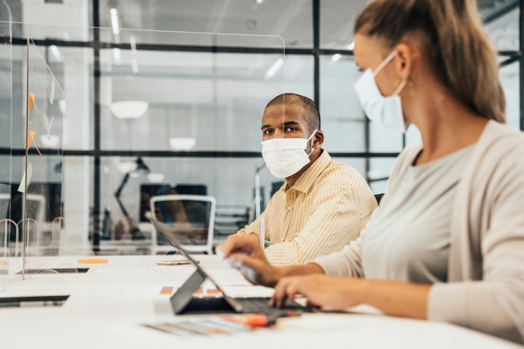Businesspeople working at office with glass partition dividing them