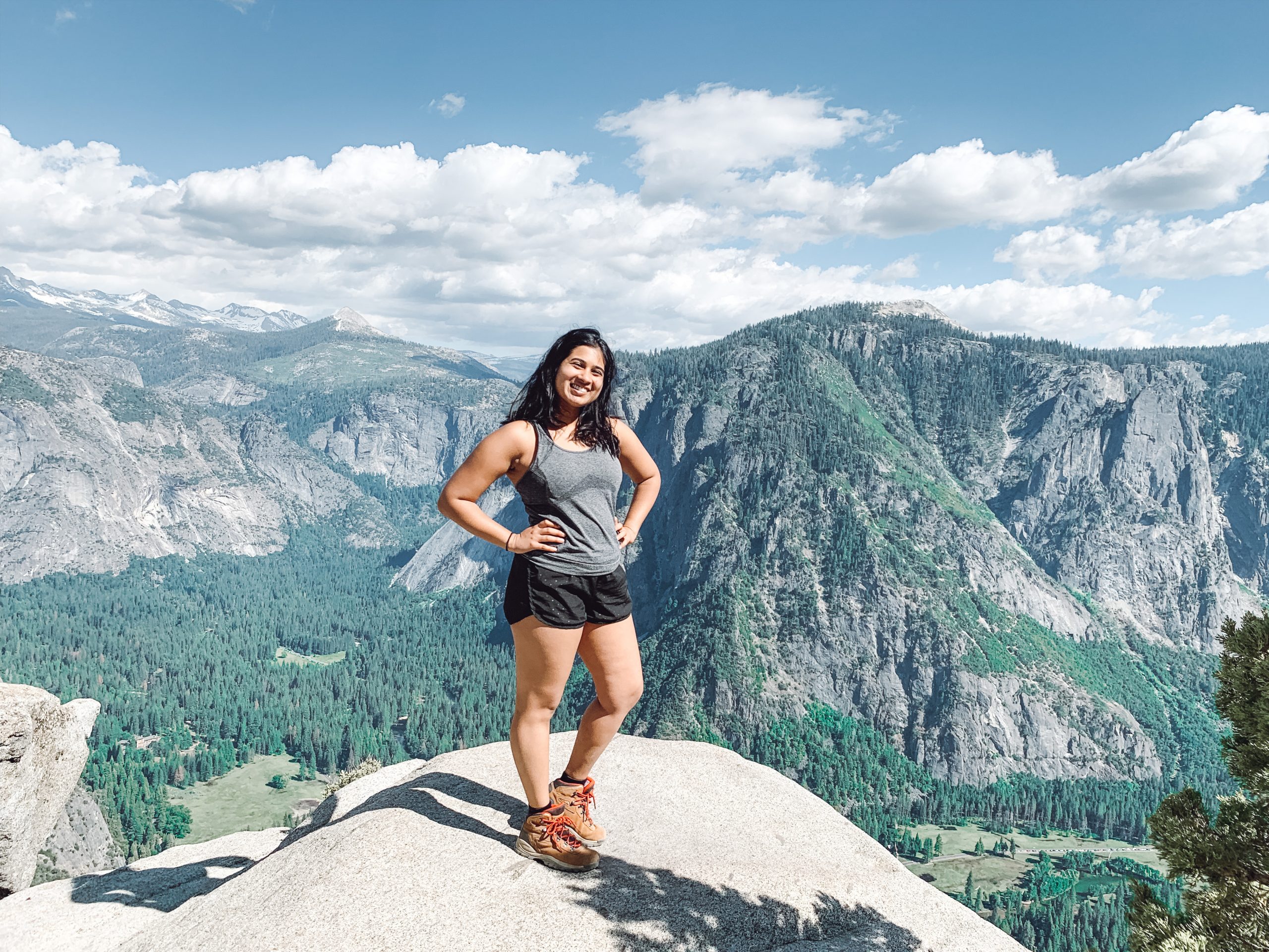 Alisha stands at the top of a mountain.