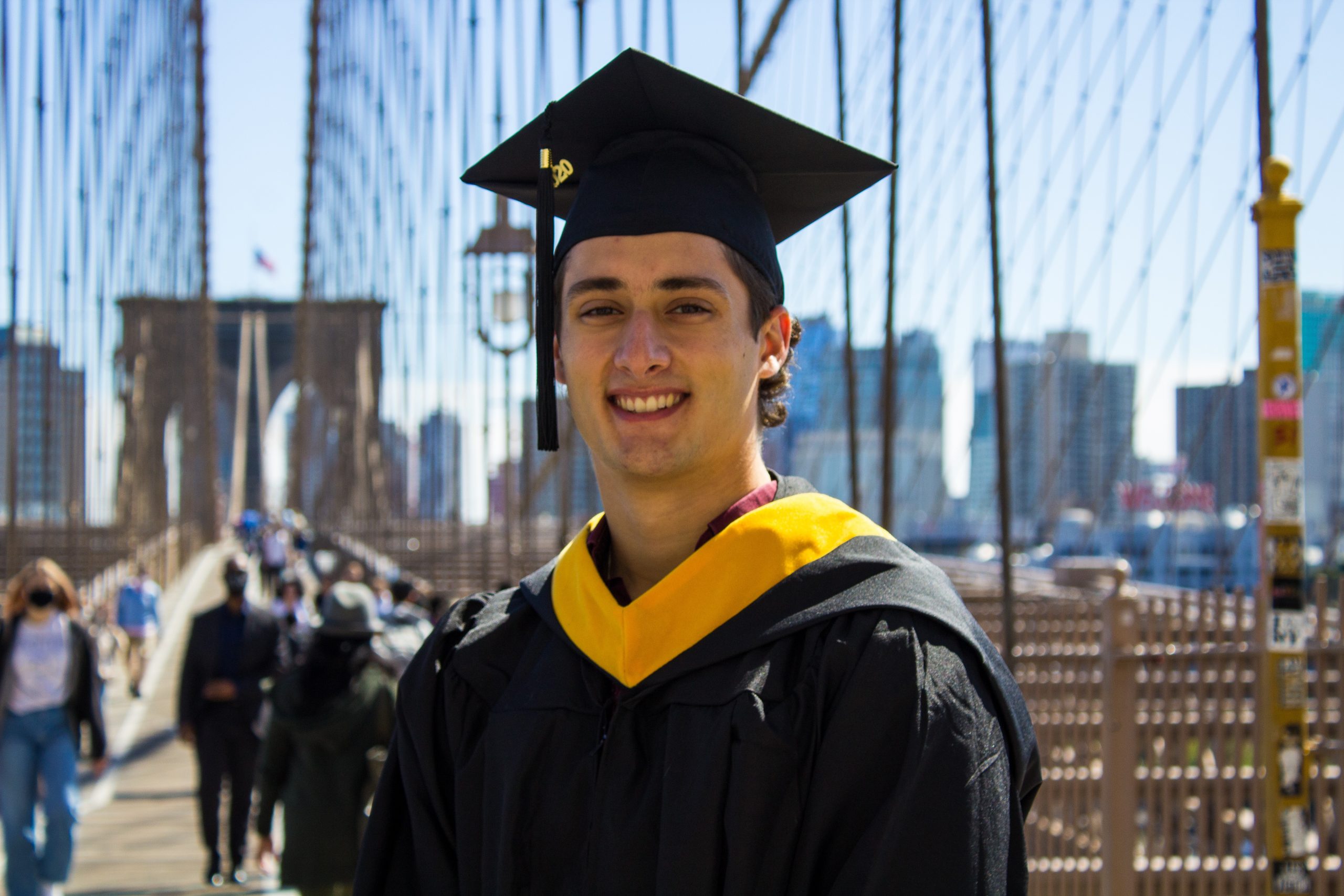 Nic standing on a bridge in cap and gown