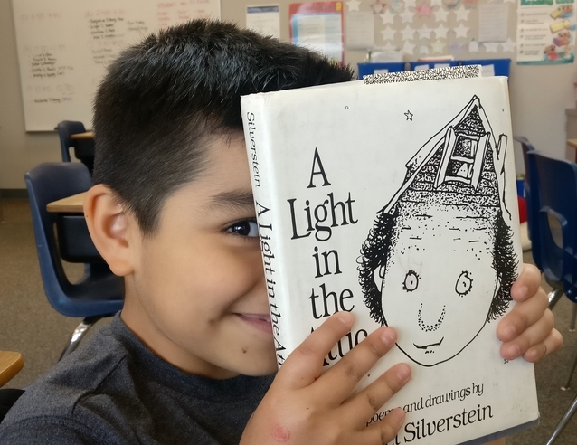 A boy holding a book up to his face