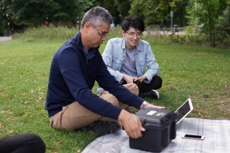 Two men sitting side by side with a device