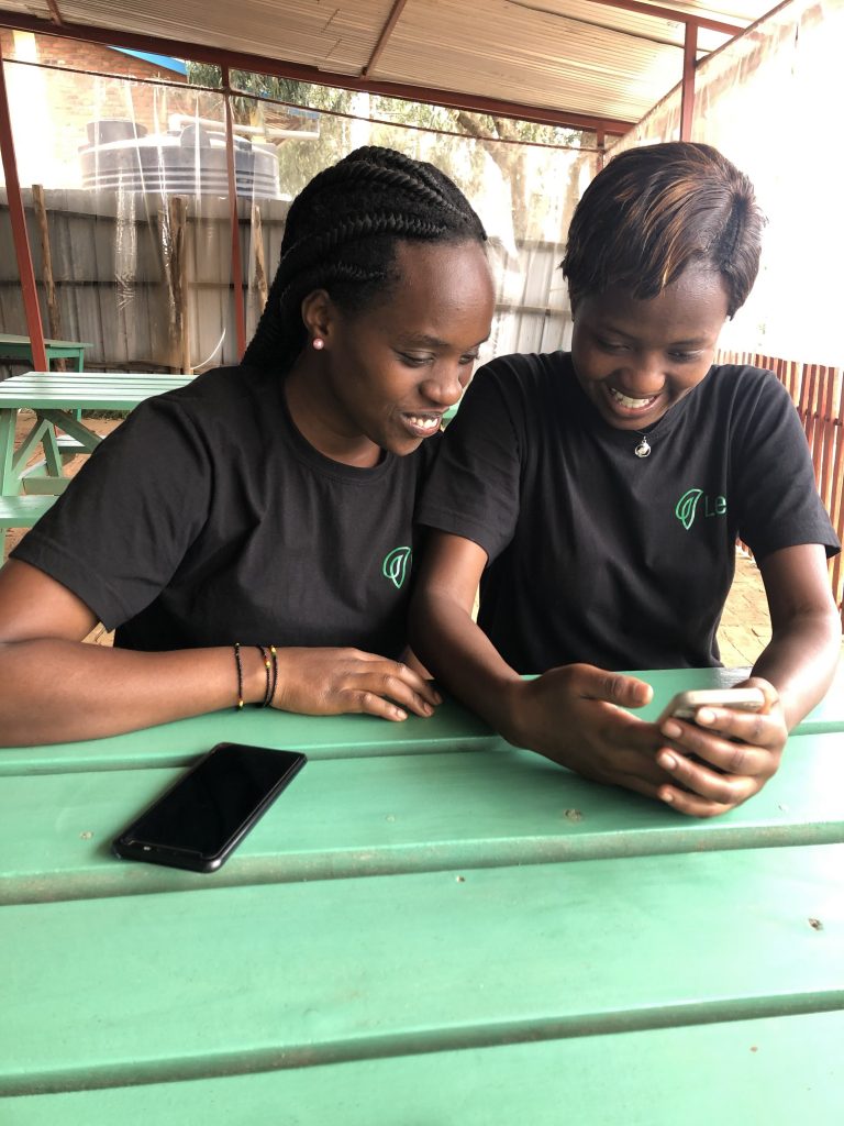 Two young women sitting side by side looking at a smartphone 