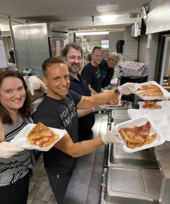 The team smiles while delivering pizzas.