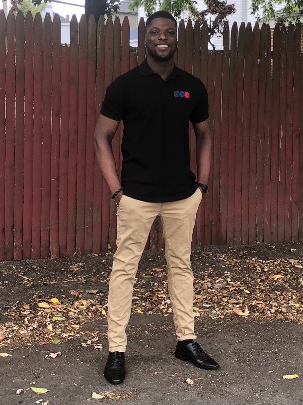 Fareed stands against a red backdrop, in a black Cisco polo.