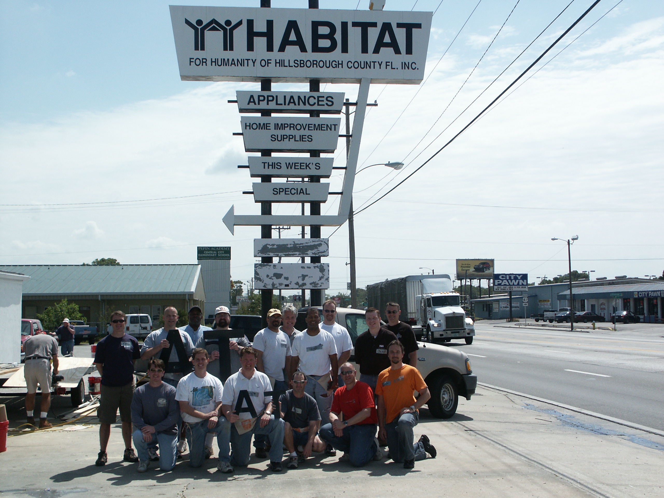 Team photo in front of Habitat for Humanity sign.