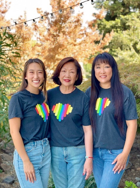 Renee, her daughter and her mother stand, smiling, while wearing Cisco Pride Heart tshirts.