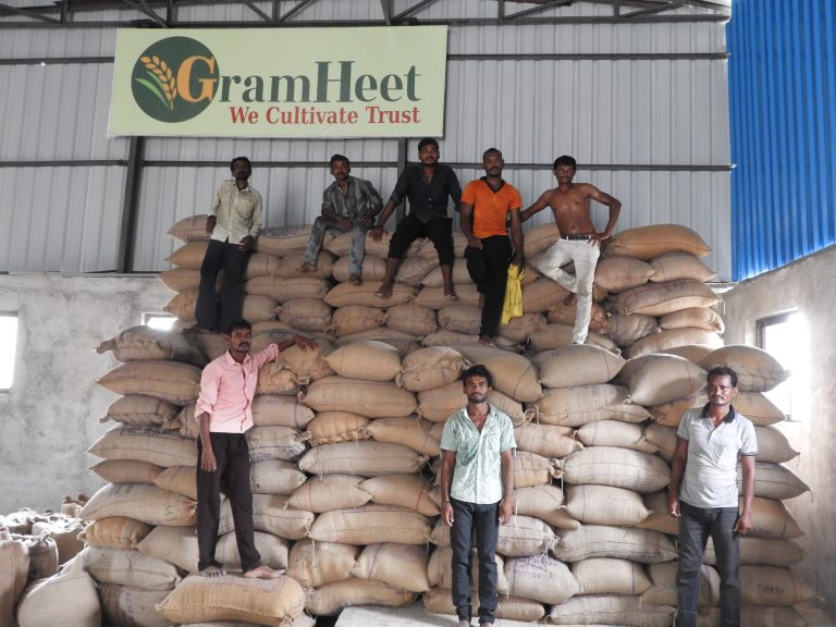 Farmers standing by a wall of grain bags