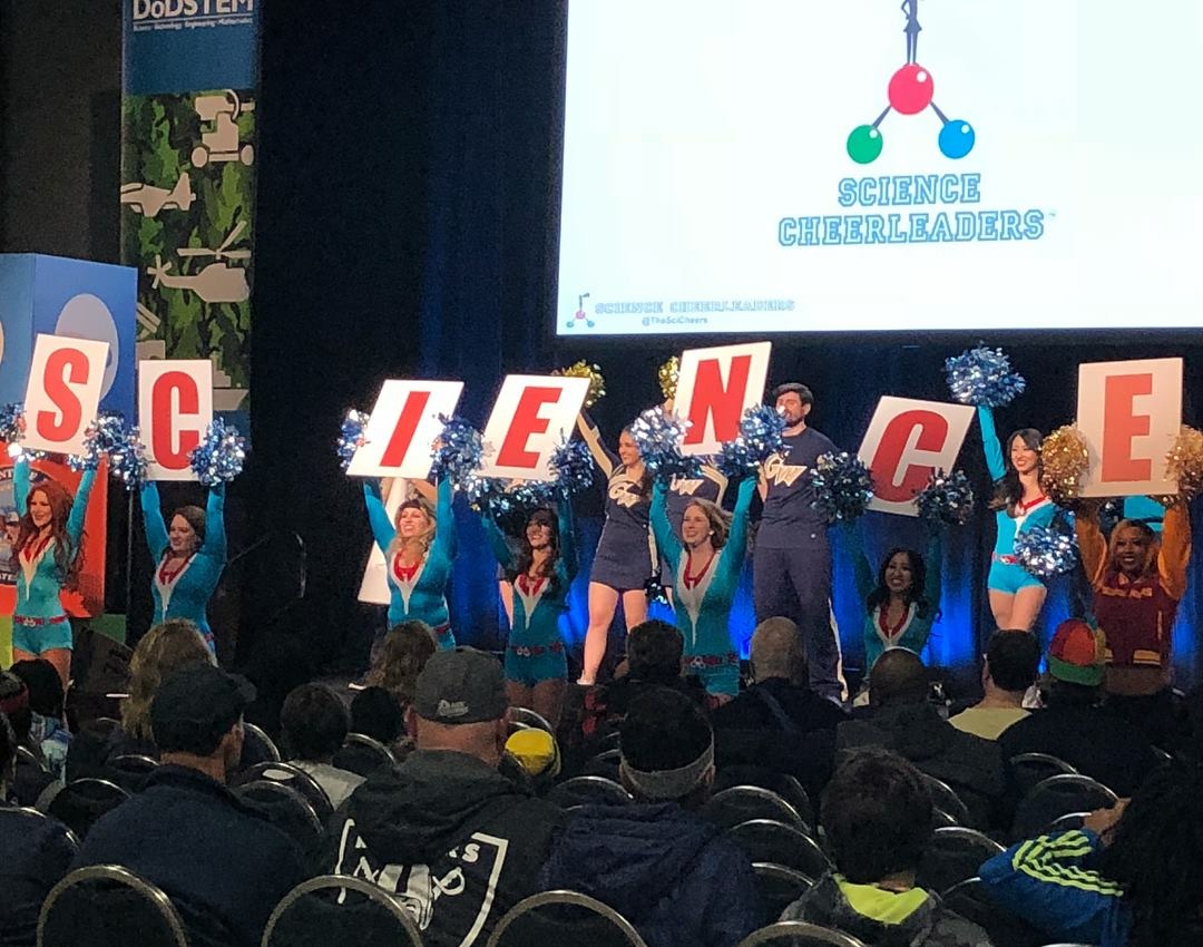 Cheerleaders holding up letter signs that spell out "science" 