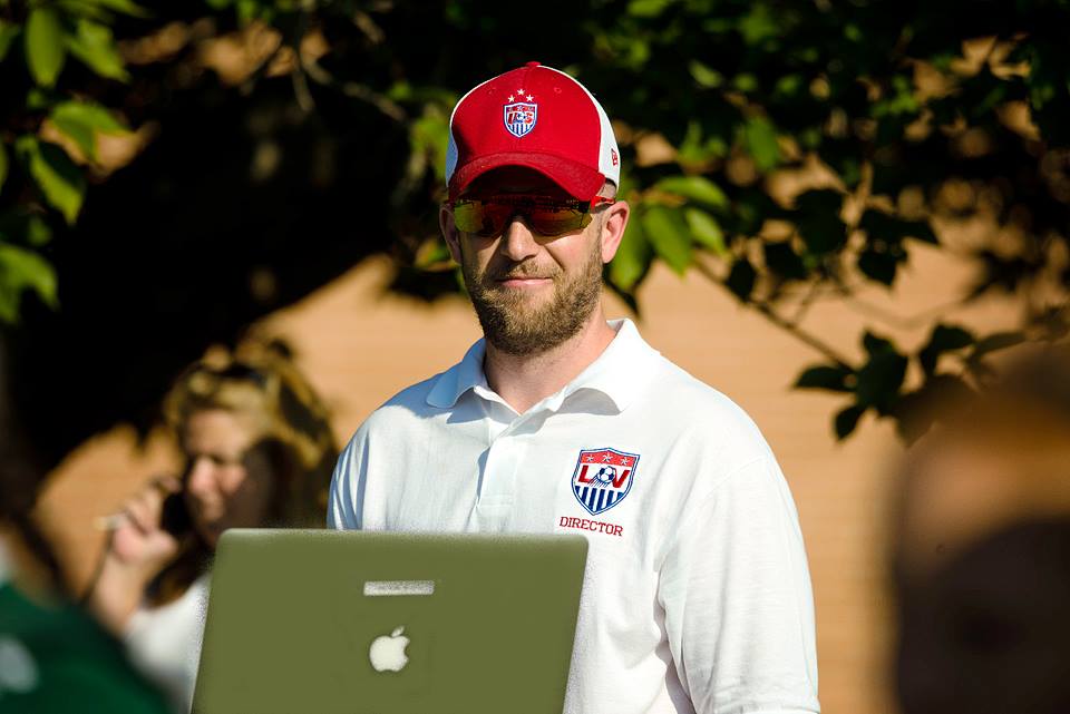 Chris working outside with a laptop at a soccer event.