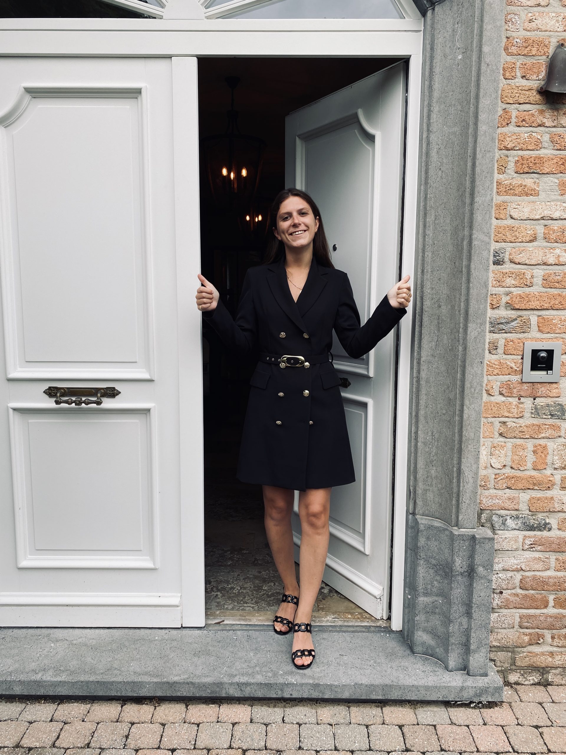 Sarah stands at her front door, two thumbs up for her first day.