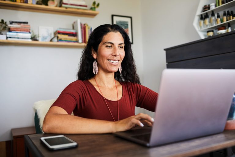 Smiling woman working on a laptop from her home office thanks to bridging remote digital divides