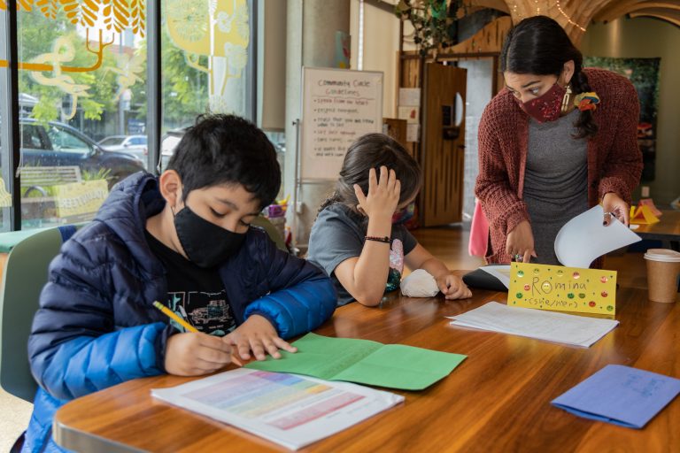A teacher with two students, all wearing masks.