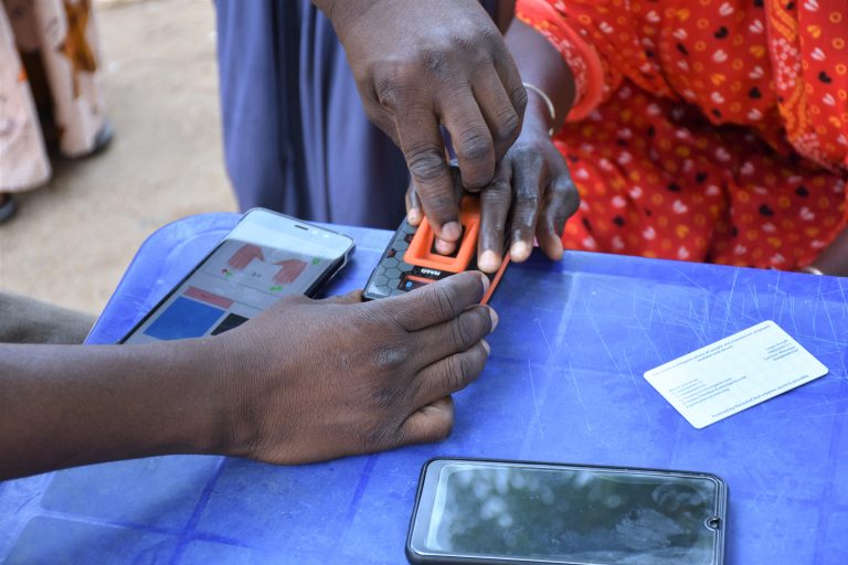 A Mercy Corps team member assists an e-voucher recipient with a digital identity process