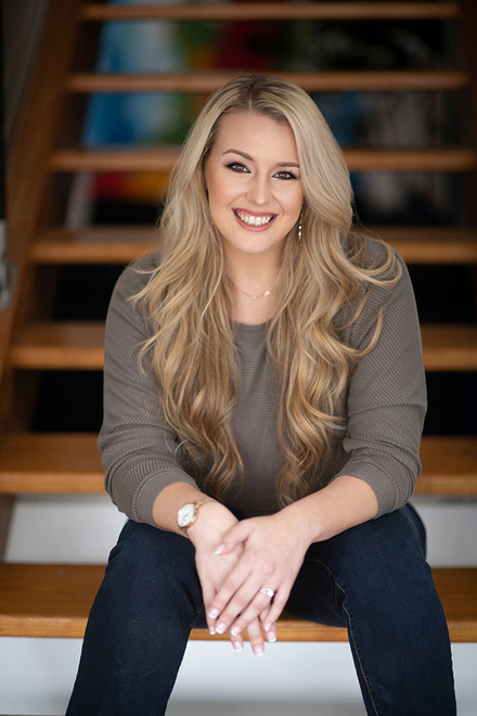 Photo of Jamelyn Bañuelos, AppDynamics customer success leader and chapter leader at AppD Cares Richardson, Texas, sitting on a staircase and smiling