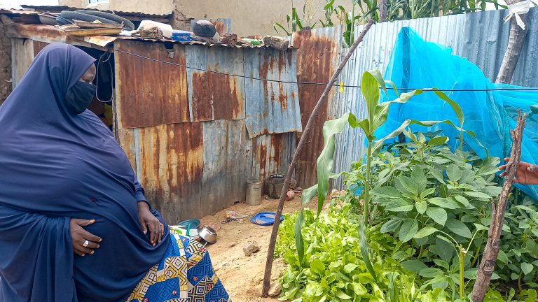 Hadiza sits in front of her small at-home garden she grew from seeds. 