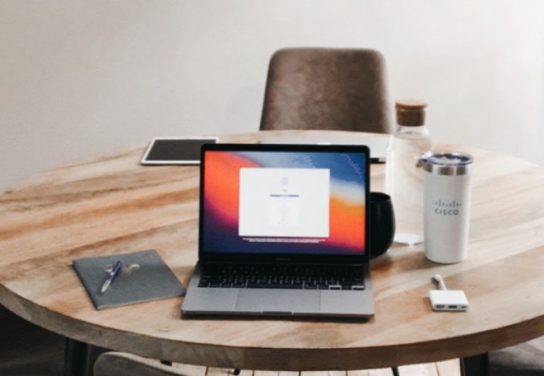 Sarah's computer sitting on a table with a Cisco coffee mug to the side.