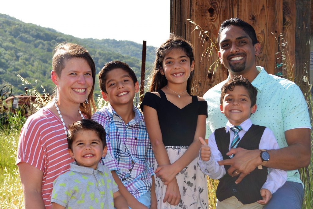 A woman and man with 4 children sitting outside.