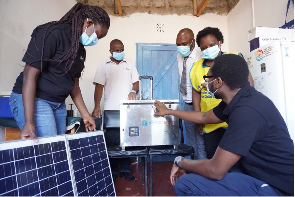 People wearing masks standing around a VacciBox