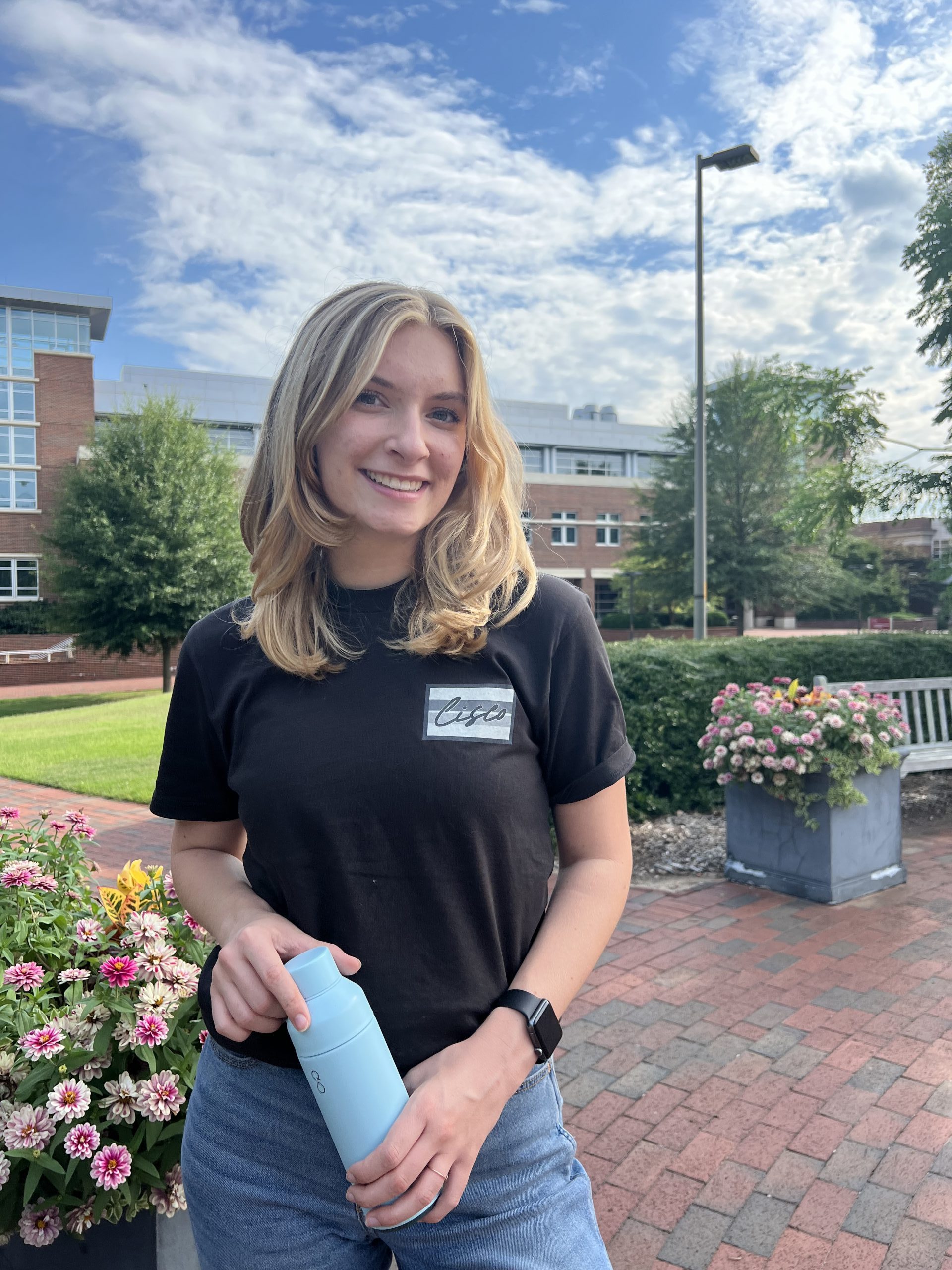 Young woman wearing black Cisco t-shirt stands in office building courtyard.