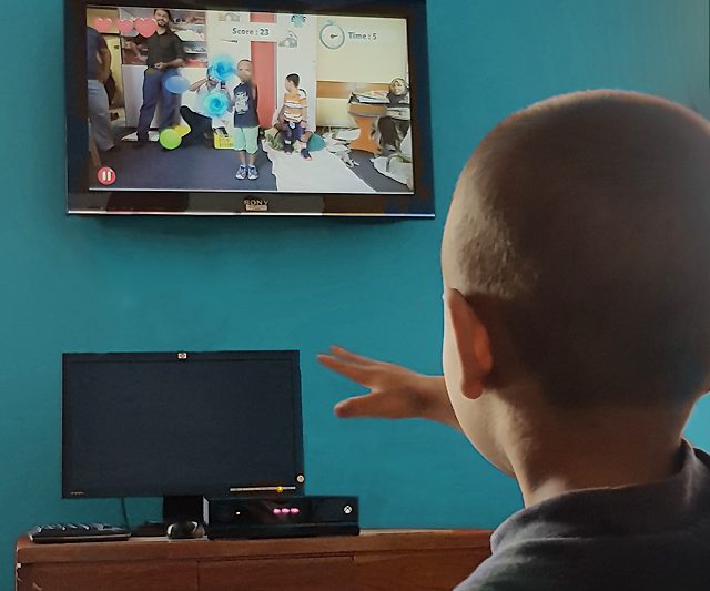 A young boy at Agha Khan University Hospital’s pediatrics department, playing along with a WonderTree interactive gamestreaming on a video monitor mounted on the wall in front of him