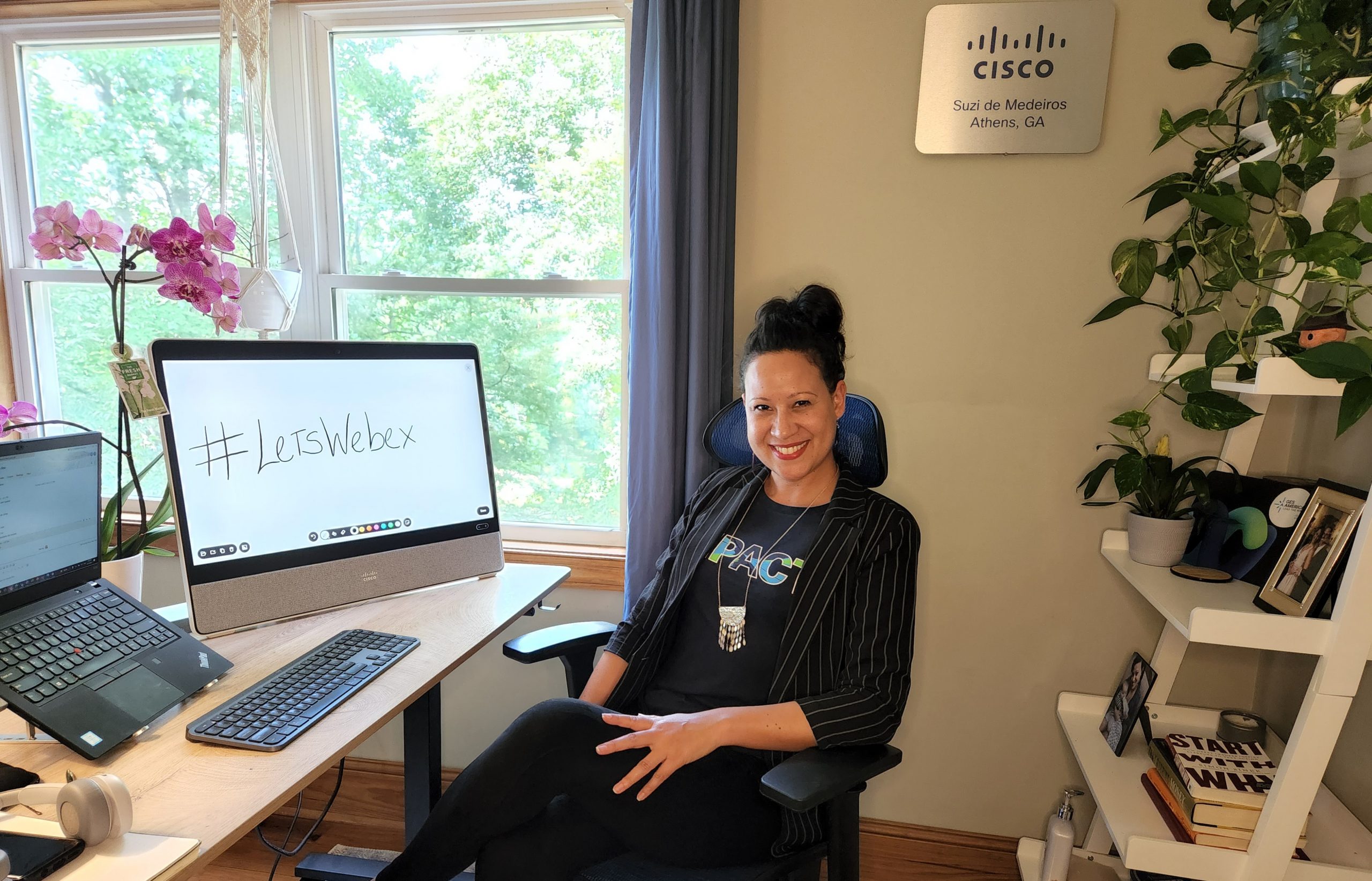 Suzi de Medeiros sits in her home office. Her computer screen reads, "#LetsWebex."