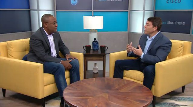 Two men sitting in plush yellow chairs having a discussion