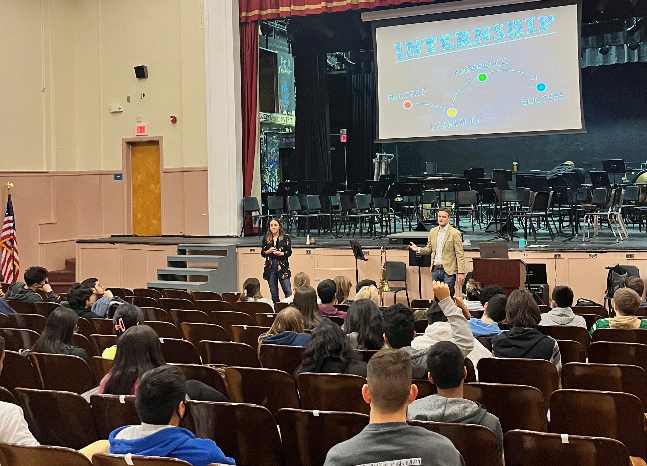 Doug and Gabby presenting to a high school auditorium 