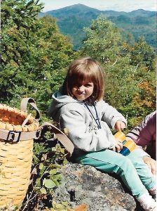 A young girl sitting on a rock in a mountain setting