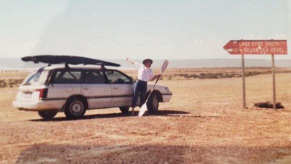 A woman standing next to a car with a canoe on top