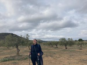 A woman smiling with her eyes closed, wearing black and using walking sticks