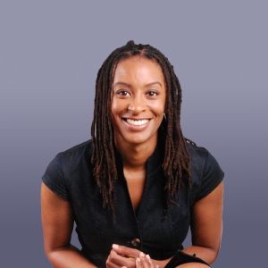 A woman smiling broadly for the camera, wearing a black top and learning forward.