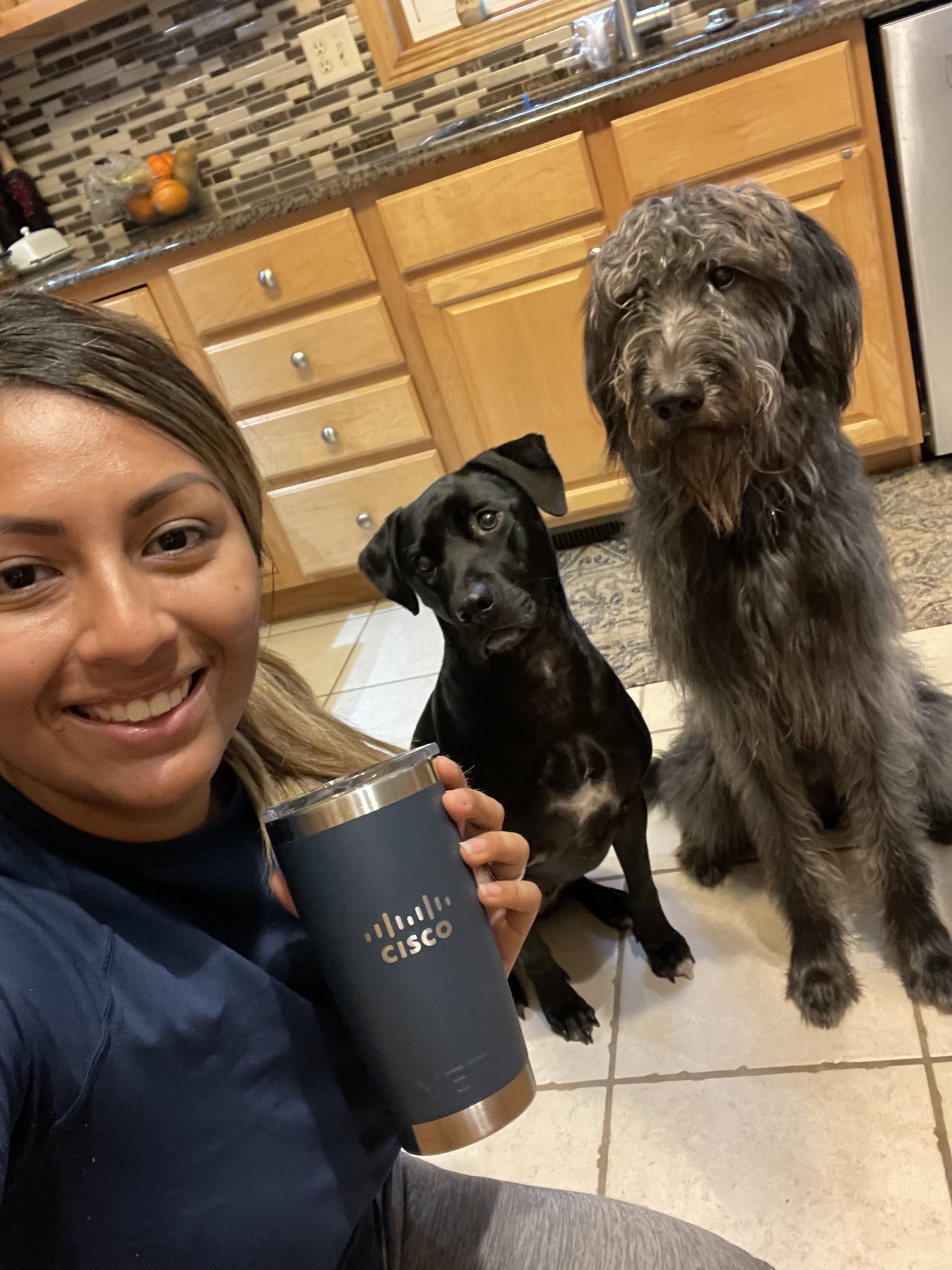 Erika holds a Cisco cup with two dogs in the background.