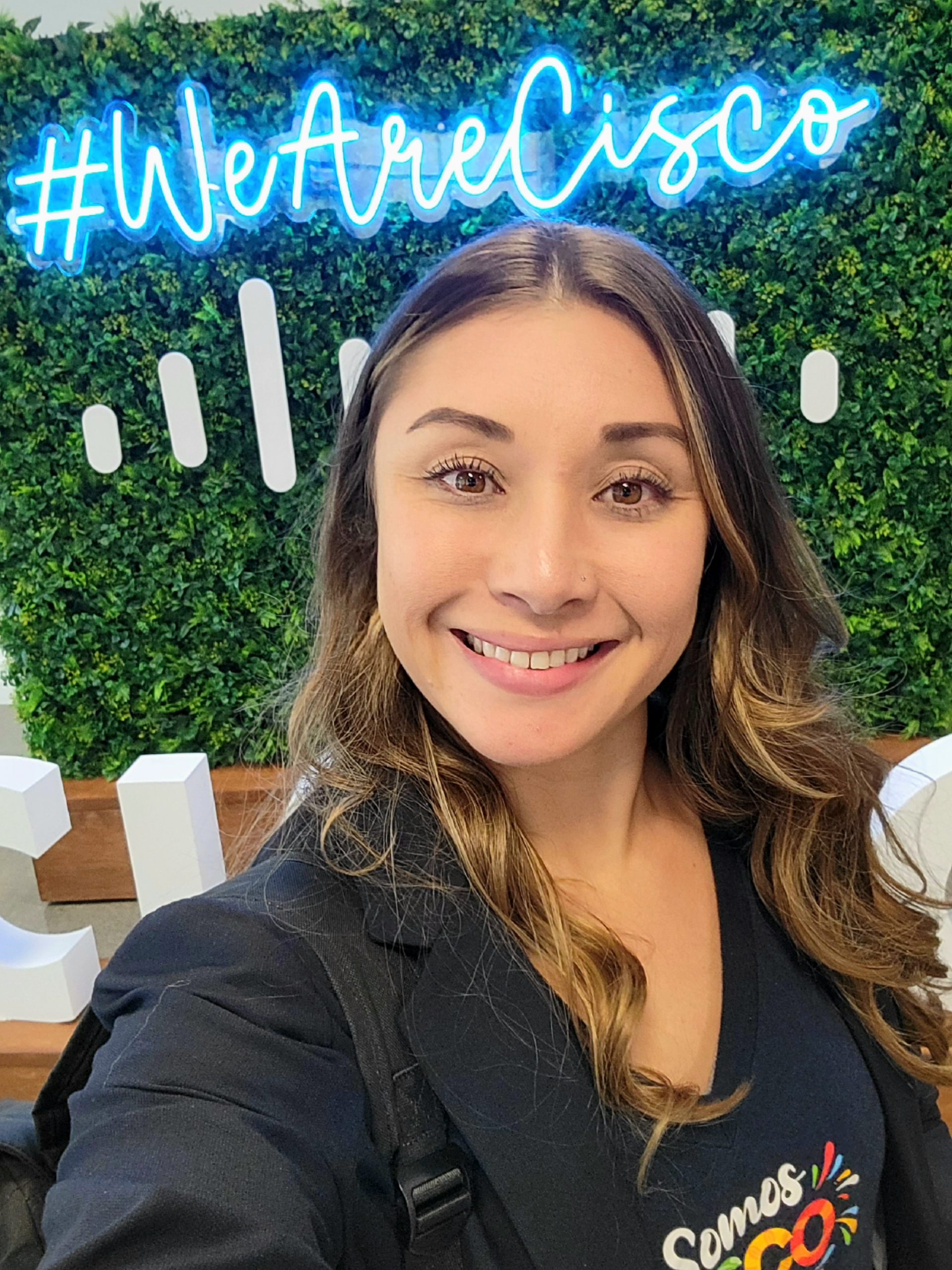 Olivia smiles with a #WeAreCisco sign in the background. 